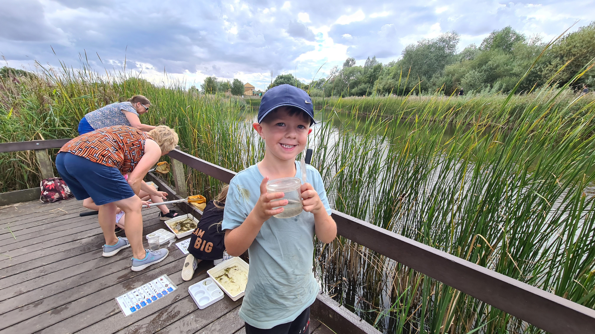children at a lake with nets dipping and looking for pond life
